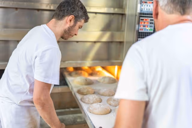 Bäcker schiebt Brotteig in den Ofen