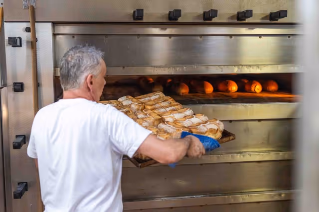 Bäcker holt gebackene Brote aus dem Ofen