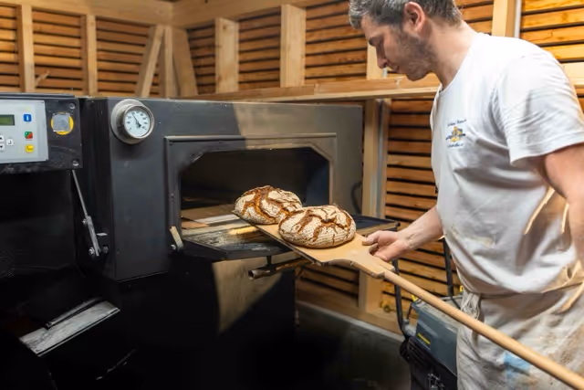 Bäcker holt frisches Brot aus dem Ofen